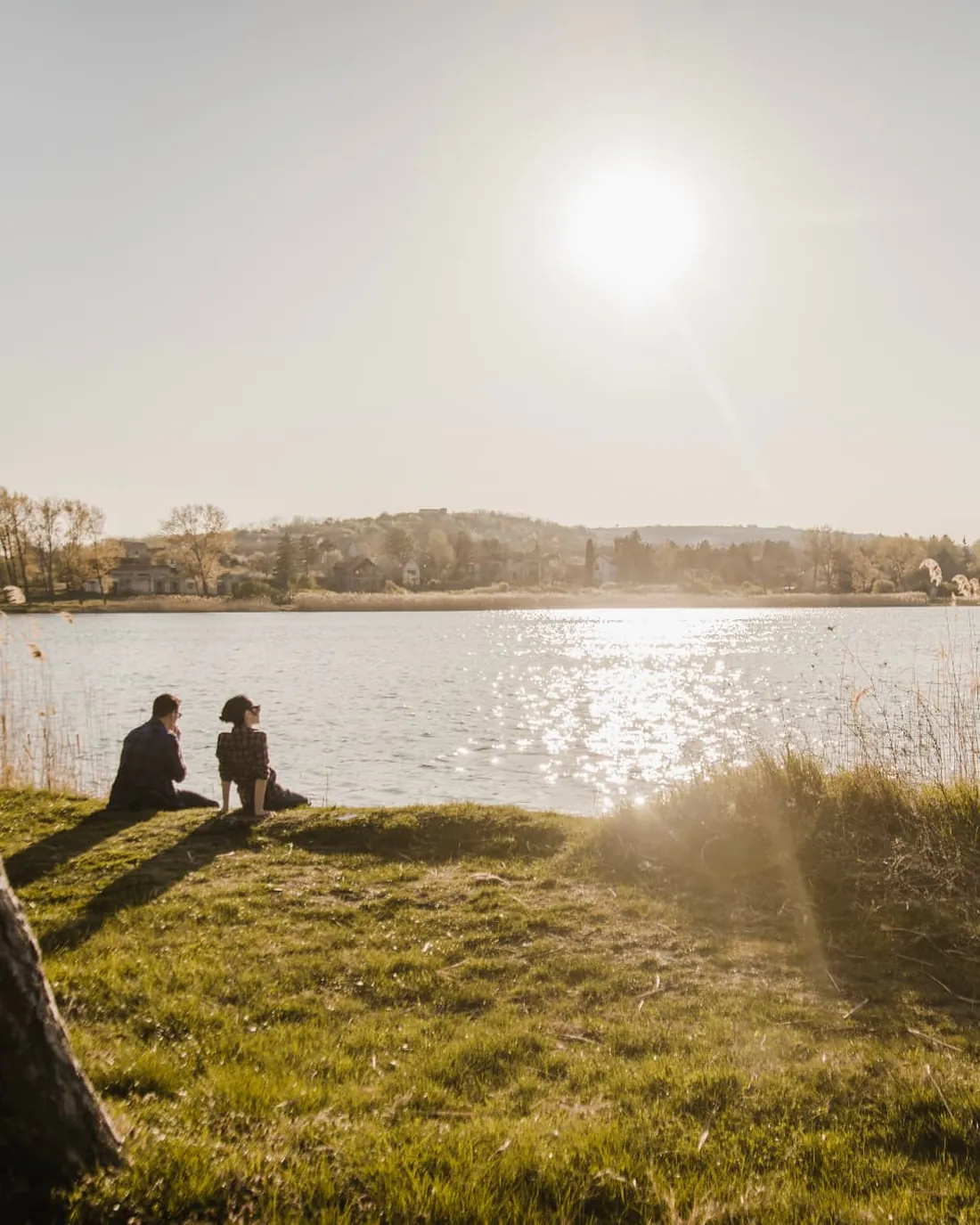 A couple sitting on the lake bank in the sunshine at Kilvington Lakes